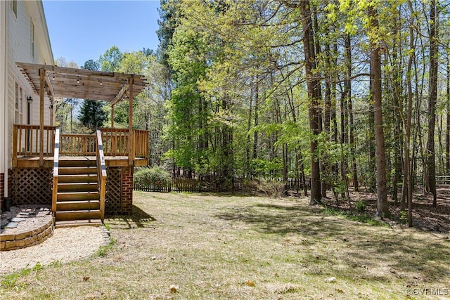view of yard with a pergola, a wooded view, fence, a wooden deck, and stairs