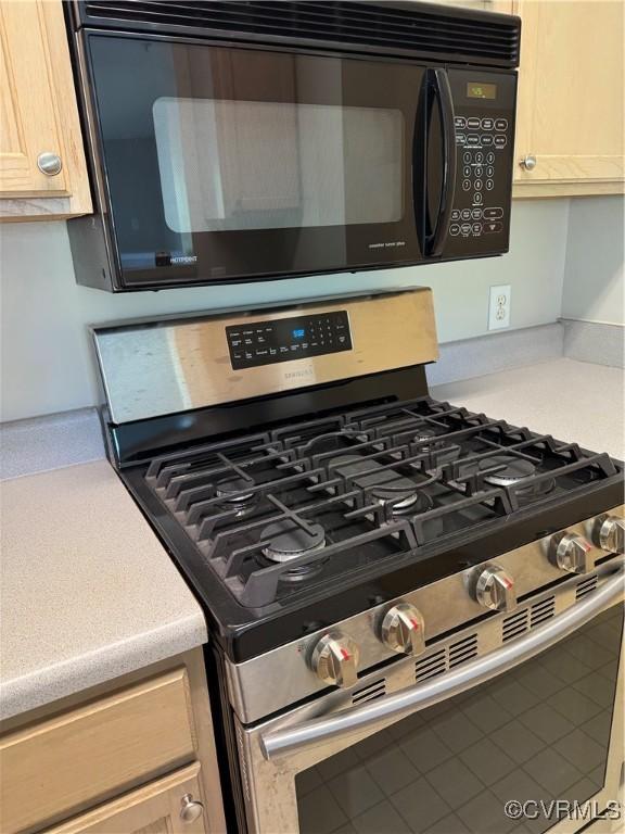 details featuring black microwave, light countertops, and stainless steel gas stove