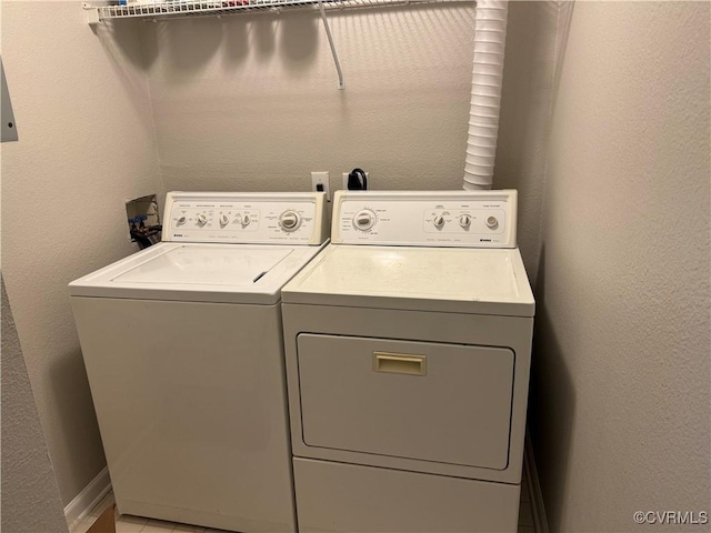 laundry area featuring independent washer and dryer, a textured wall, baseboards, and laundry area