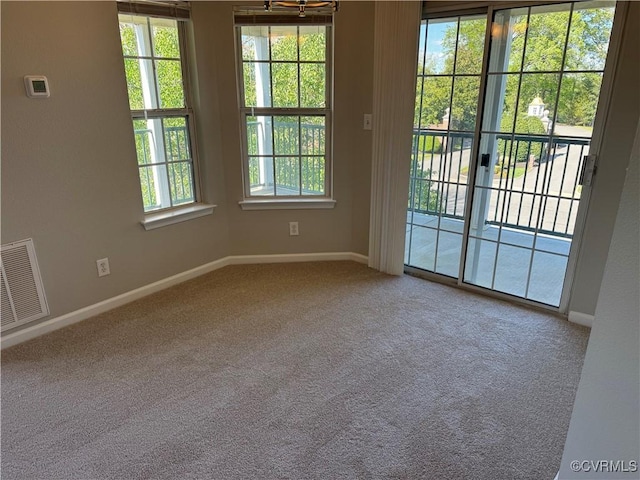 spare room with carpet floors, visible vents, and baseboards