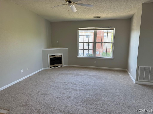 unfurnished living room featuring a fireplace, a textured ceiling, carpet, and visible vents
