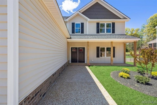 view of exterior entry featuring a porch, a yard, and board and batten siding