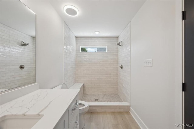 bathroom featuring a tile shower, toilet, and wood finished floors