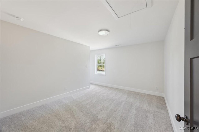 carpeted empty room with attic access and baseboards