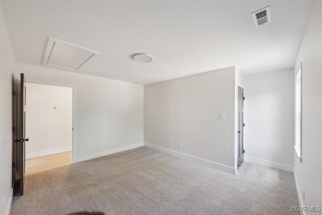 empty room with attic access, carpet, visible vents, and baseboards