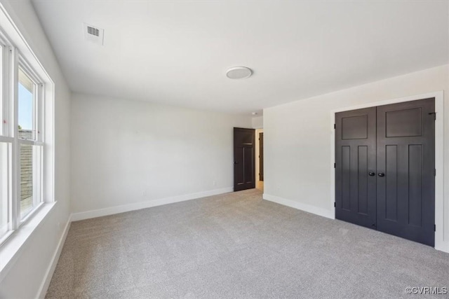 empty room featuring visible vents, light carpet, and baseboards