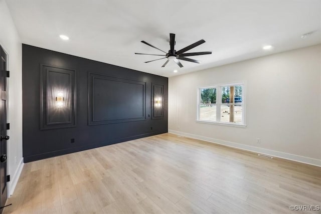 empty room featuring baseboards, a ceiling fan, and light wood-style flooring