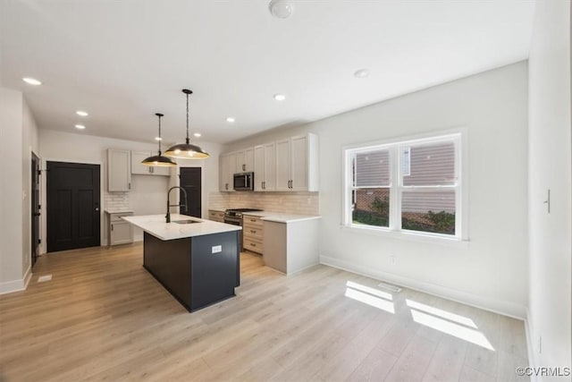 kitchen featuring tasteful backsplash, appliances with stainless steel finishes, baseboards, and a sink