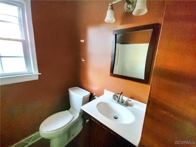 bathroom with plenty of natural light, toilet, and vanity