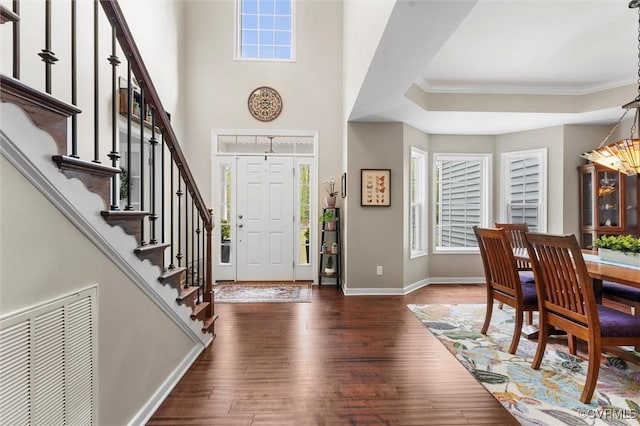 foyer entrance with baseboards, visible vents, stairway, hardwood / wood-style floors, and ornamental molding