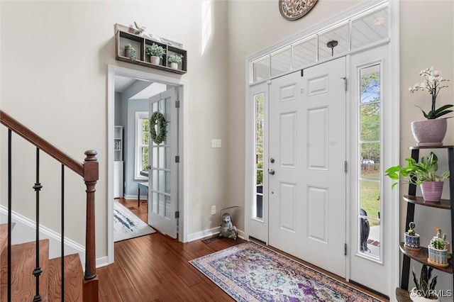 foyer entrance with stairway, a wealth of natural light, wood finished floors, and baseboards