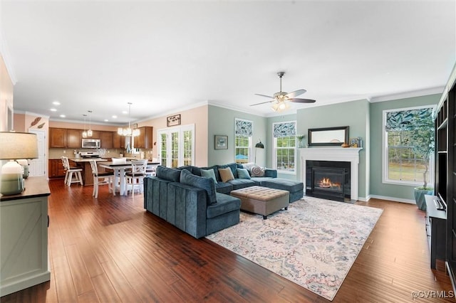 living room featuring a fireplace with flush hearth, a wealth of natural light, crown molding, and dark wood-type flooring
