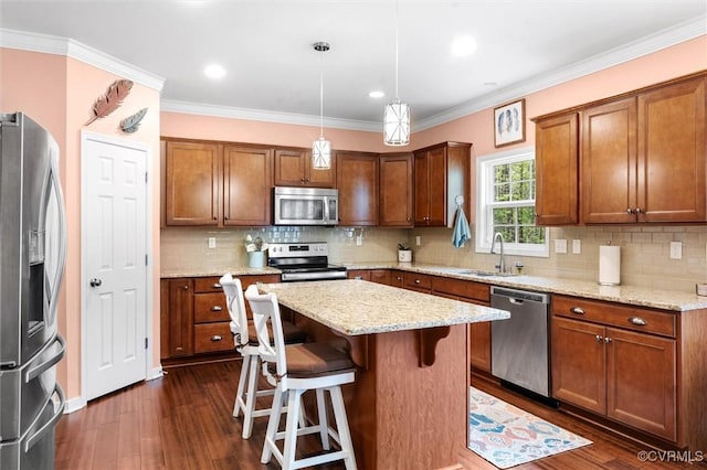 kitchen with a kitchen breakfast bar, a sink, brown cabinetry, appliances with stainless steel finishes, and dark wood-style flooring