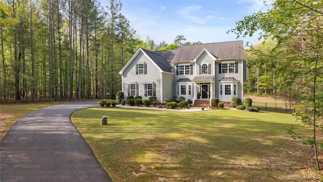 view of front facade with fence, driveway, and a front yard