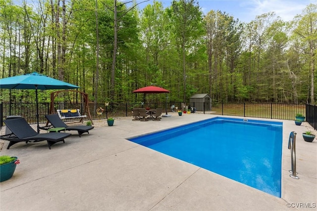 view of pool featuring a patio area, fence, an outbuilding, a fenced in pool, and a storage unit