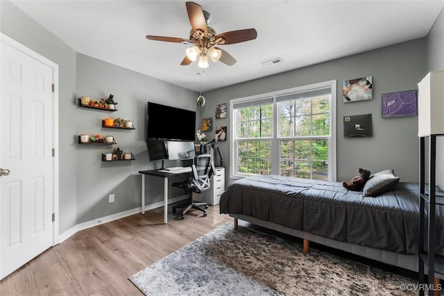 bedroom with wood finished floors, visible vents, a ceiling fan, and baseboards