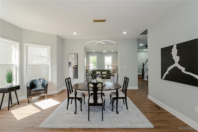 dining space with wood finished floors, visible vents, and baseboards