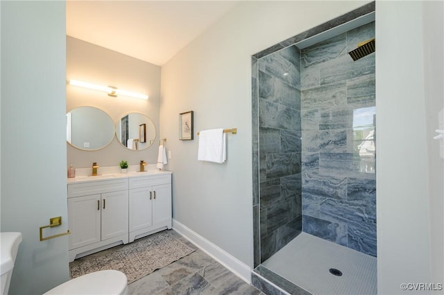bathroom featuring a sink, double vanity, baseboards, a tile shower, and toilet