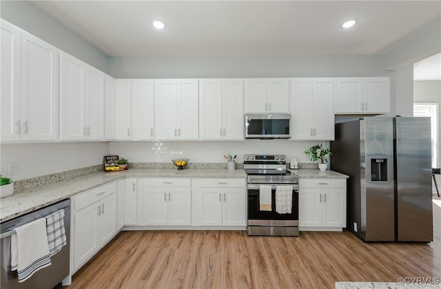 kitchen with white cabinets, light wood-style flooring, and appliances with stainless steel finishes