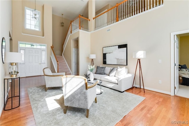 living area with light wood-style flooring, a high ceiling, and stairway