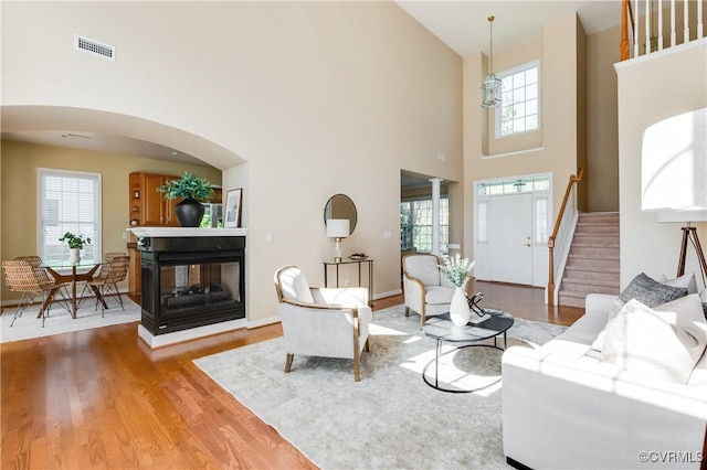 living area featuring a high ceiling, wood finished floors, visible vents, and a wealth of natural light