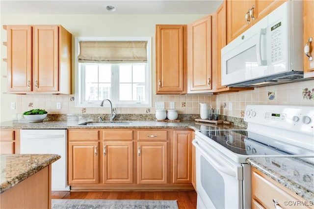 kitchen featuring a sink, white appliances, light wood-type flooring, light stone countertops, and decorative backsplash