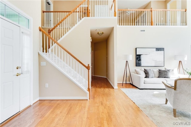 entrance foyer featuring stairway, wood finished floors, a towering ceiling, baseboards, and visible vents