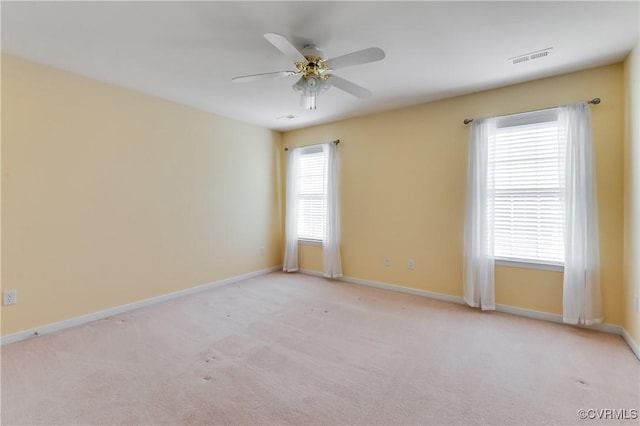 carpeted empty room with ceiling fan, baseboards, and visible vents