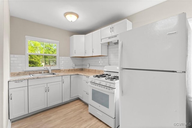 kitchen with under cabinet range hood, light countertops, a sink, white appliances, and light wood-type flooring
