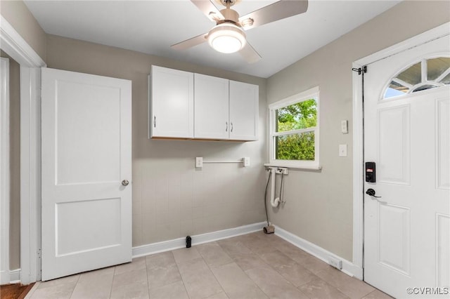washroom featuring a ceiling fan, baseboards, cabinet space, and light tile patterned floors