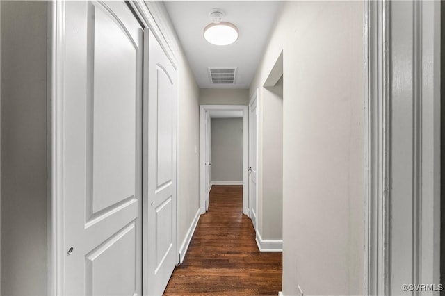 corridor with baseboards, dark wood-style flooring, and visible vents