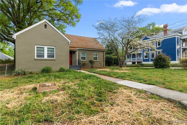 bungalow featuring stucco siding and a front lawn