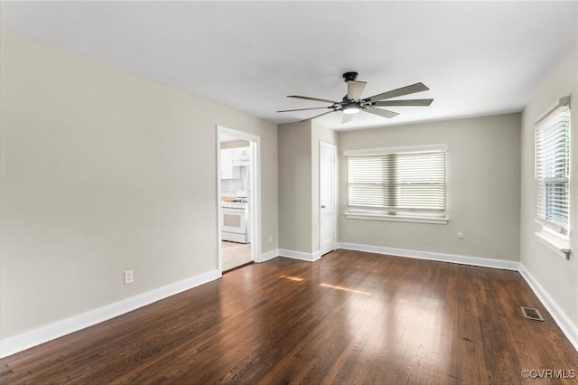 unfurnished room featuring baseboards, visible vents, dark wood-style floors, and ceiling fan