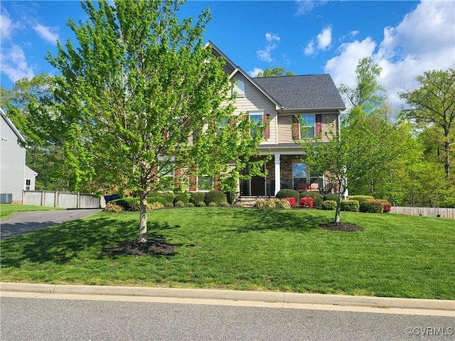 view of front of property featuring stone siding, a porch, fence, and a front yard