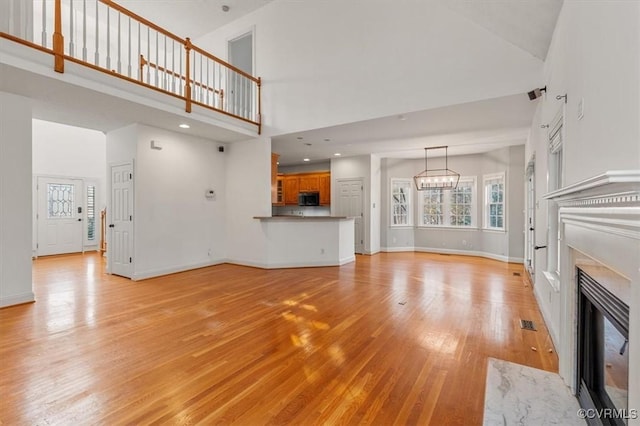 11107 Lyndenwood Dr, Chesterfield, VA 23838 - unfurnished living room with light wood-type flooring, a towering ceiling, a fireplace, baseboards, and visible vents