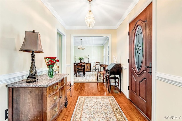 foyer featuring crown molding, wood finished floors, and a chandelier