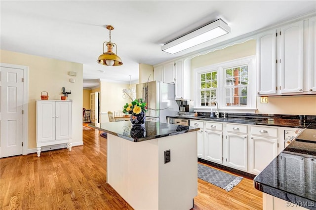 kitchen featuring white cabinets, hanging light fixtures, light wood finished floors, freestanding refrigerator, and a kitchen island