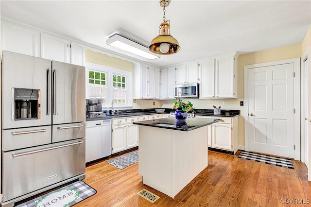 kitchen featuring stainless steel appliances, dark countertops, white cabinetry, and light wood-type flooring