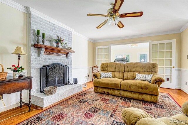 living room featuring crown molding, ceiling fan, wood finished floors, and a fireplace