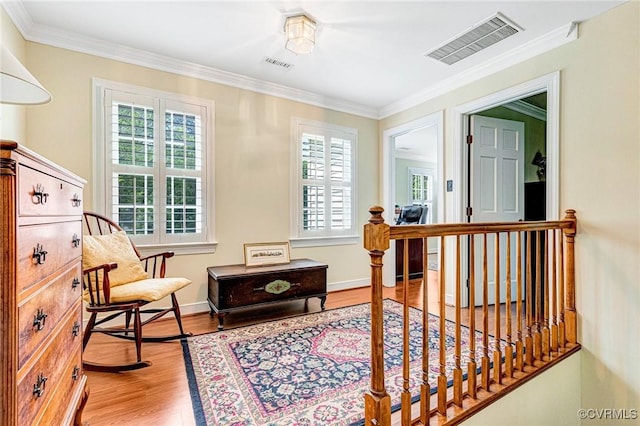 living area featuring visible vents, baseboards, crown molding, and wood finished floors