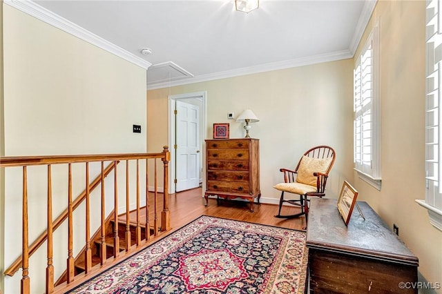 sitting room with a healthy amount of sunlight, ornamental molding, attic access, and wood finished floors