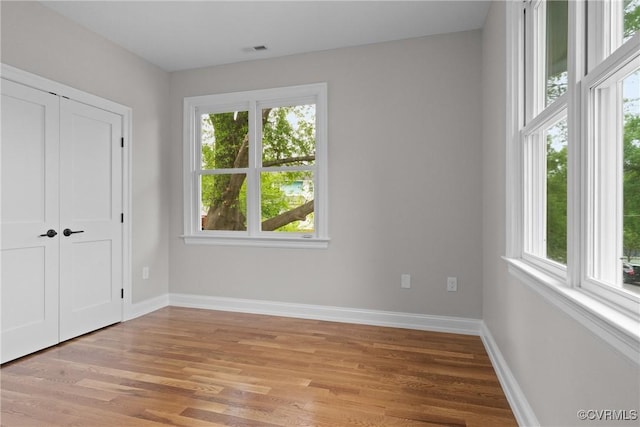 unfurnished bedroom with visible vents, light wood finished floors, and multiple windows