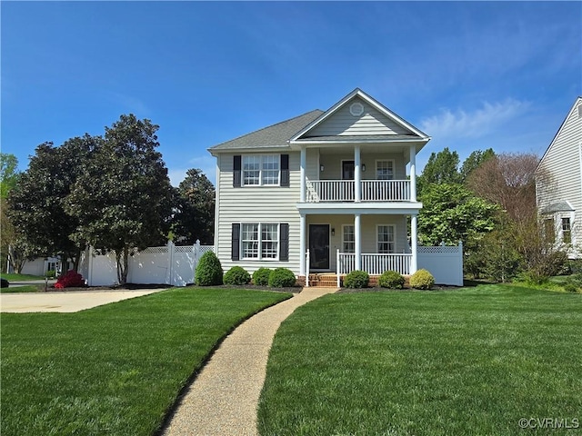 neoclassical / greek revival house with fence, covered porch, a front yard, and a balcony