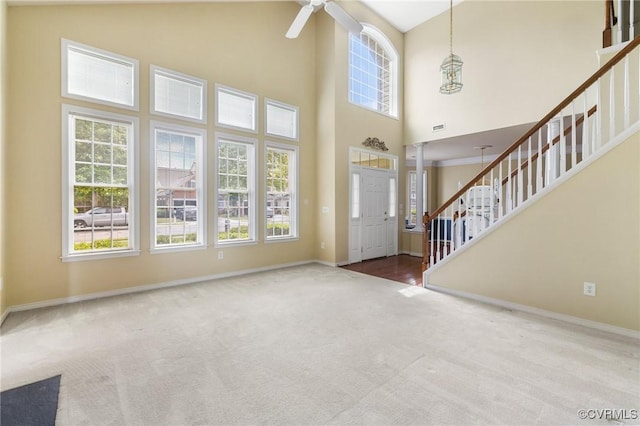 carpeted foyer with plenty of natural light, stairway, and baseboards
