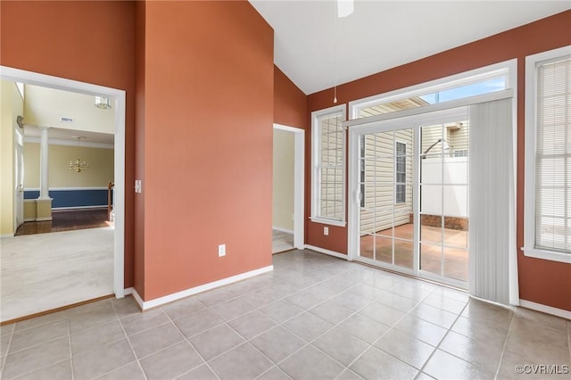 empty room with lofted ceiling, a wealth of natural light, baseboards, and ornate columns