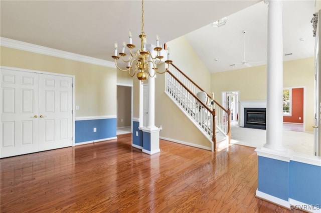 unfurnished living room featuring wood finished floors, baseboards, a glass covered fireplace, a chandelier, and stairs