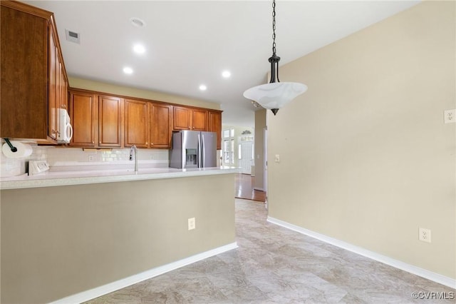 kitchen with recessed lighting, brown cabinetry, visible vents, a peninsula, and stainless steel fridge