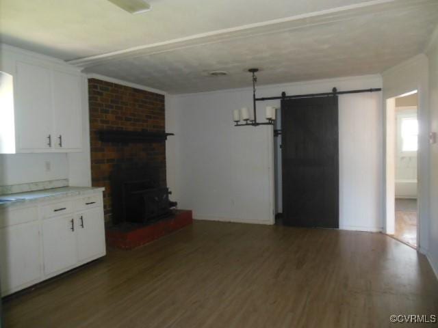 unfurnished living room with wood finished floors, a wood stove, and a barn door