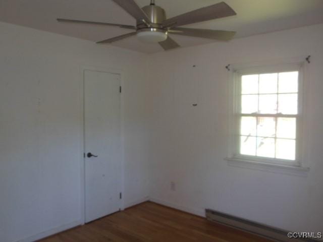 spare room with a ceiling fan, wood finished floors, and a baseboard radiator