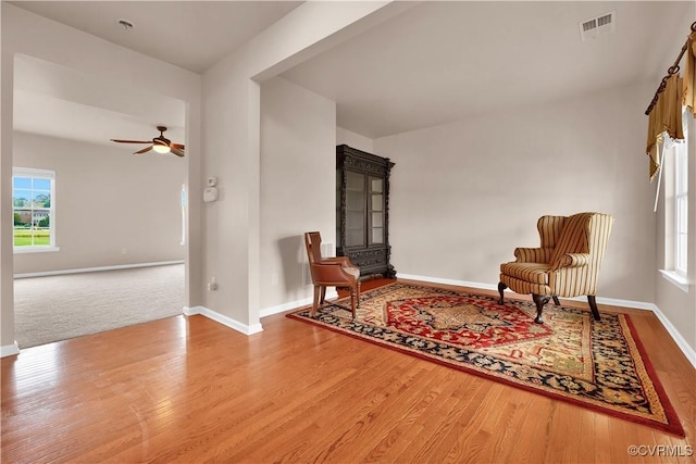 living area featuring healthy amount of natural light, wood finished floors, ceiling fan, and baseboards